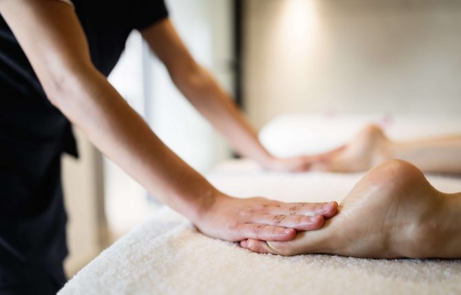 Masseuse masaging feet of person at massage salon