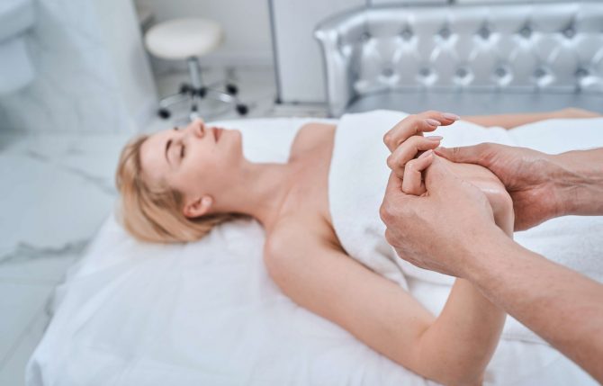 Blonde woman lying supine on the couch during the acupressure massage performed by a reflexologist